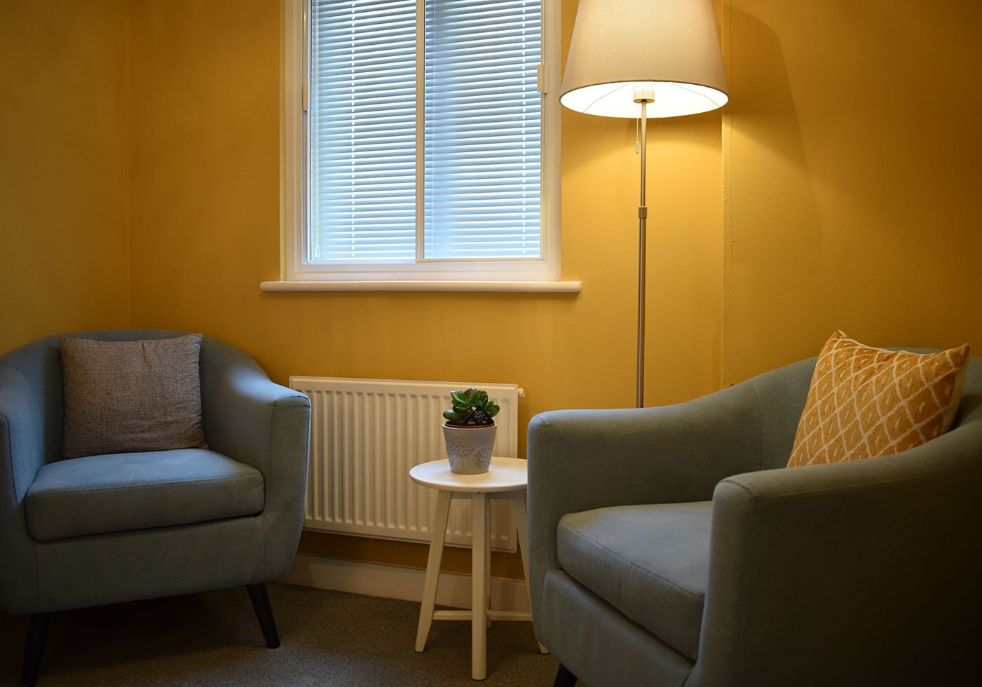 BalanceHealth private face-to-face CBT therapy room at 8, Abbey Meads Village Centre, Swindon SN25 4YX, featuring two comfortable sage armchairs and warm ambient lamp lighting